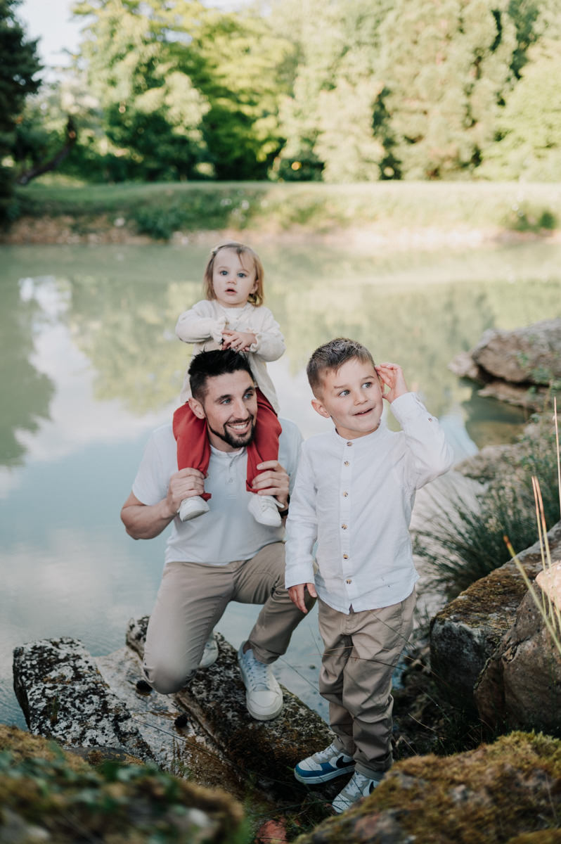 papa porte sa fille sur ses épaule avec son grand frère à côté de lui